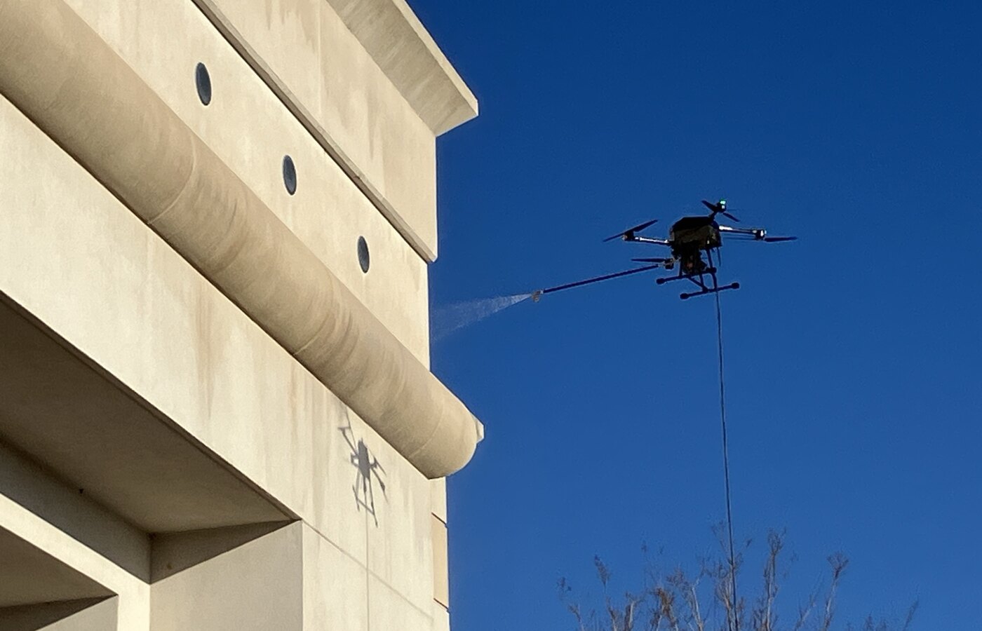 Commercial washing drone applying a controlled spray to a building facade