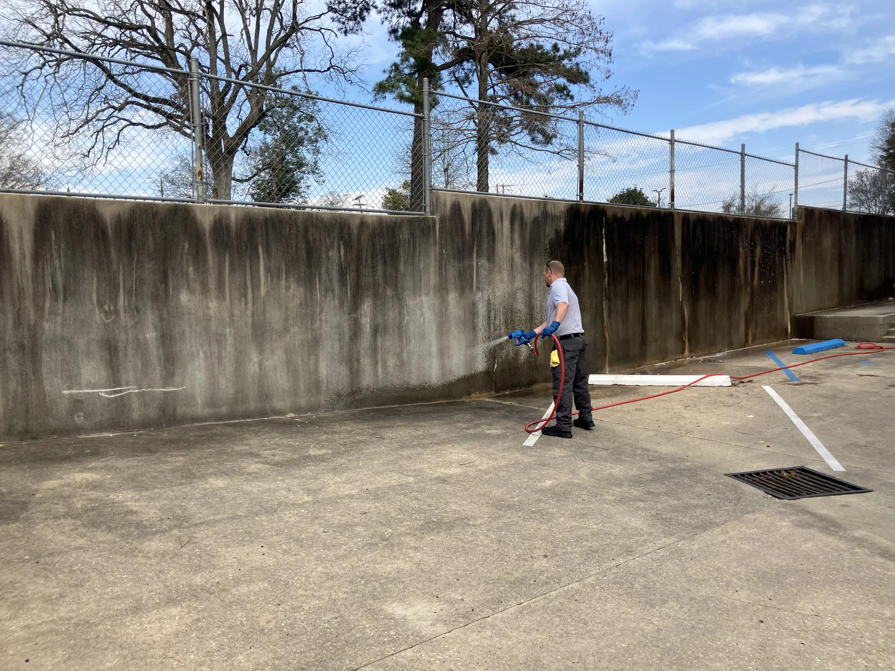 Worker using a pressure washing wand along an exterior wall