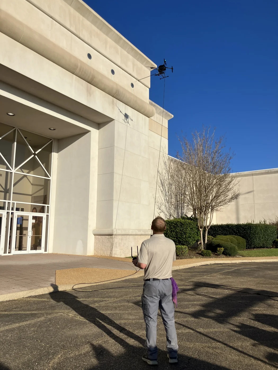 Commercial washing drone working beside a tall pale exterior wall